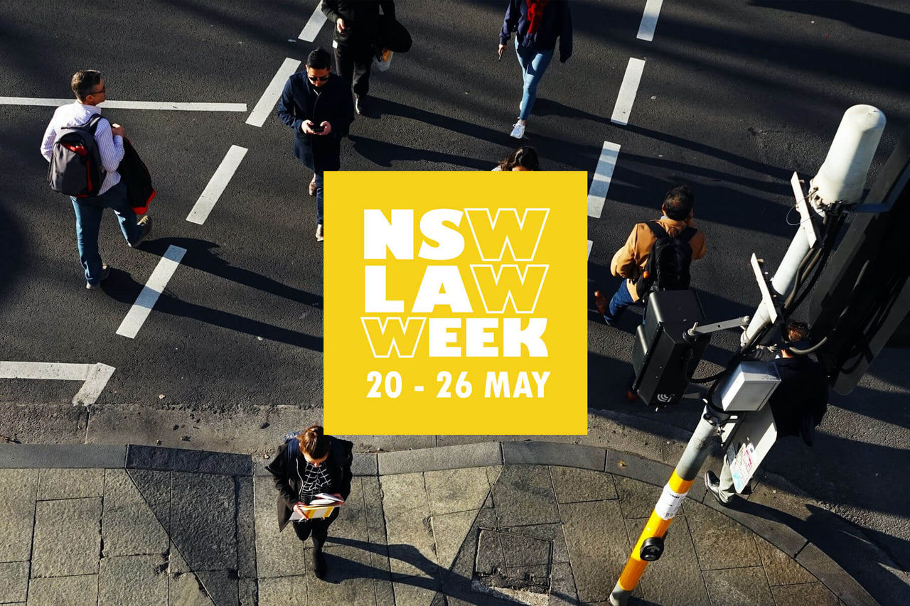 Pedestrians crossing at a busy intersection, with the Law Week NSW logo placed in the middle of the image.