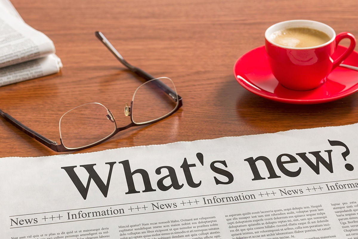 A newspaper shows a heading saying what's new with a pair of glasses and a coffee sitting nearby