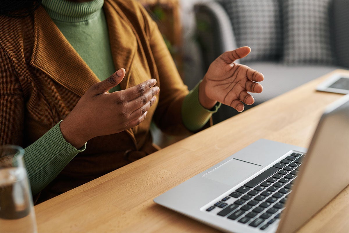 Person in front of a computer with only their torso showing. Their hands are up as if they are explaining something.