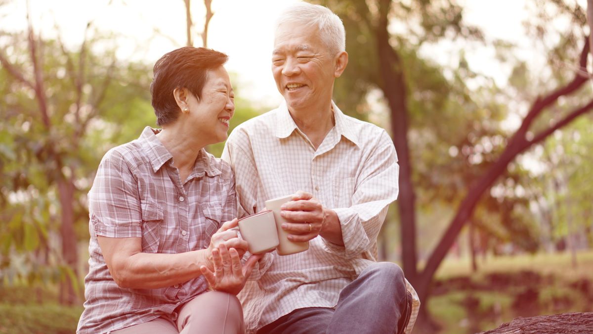 Asian senior couple sitting outside having a coffee