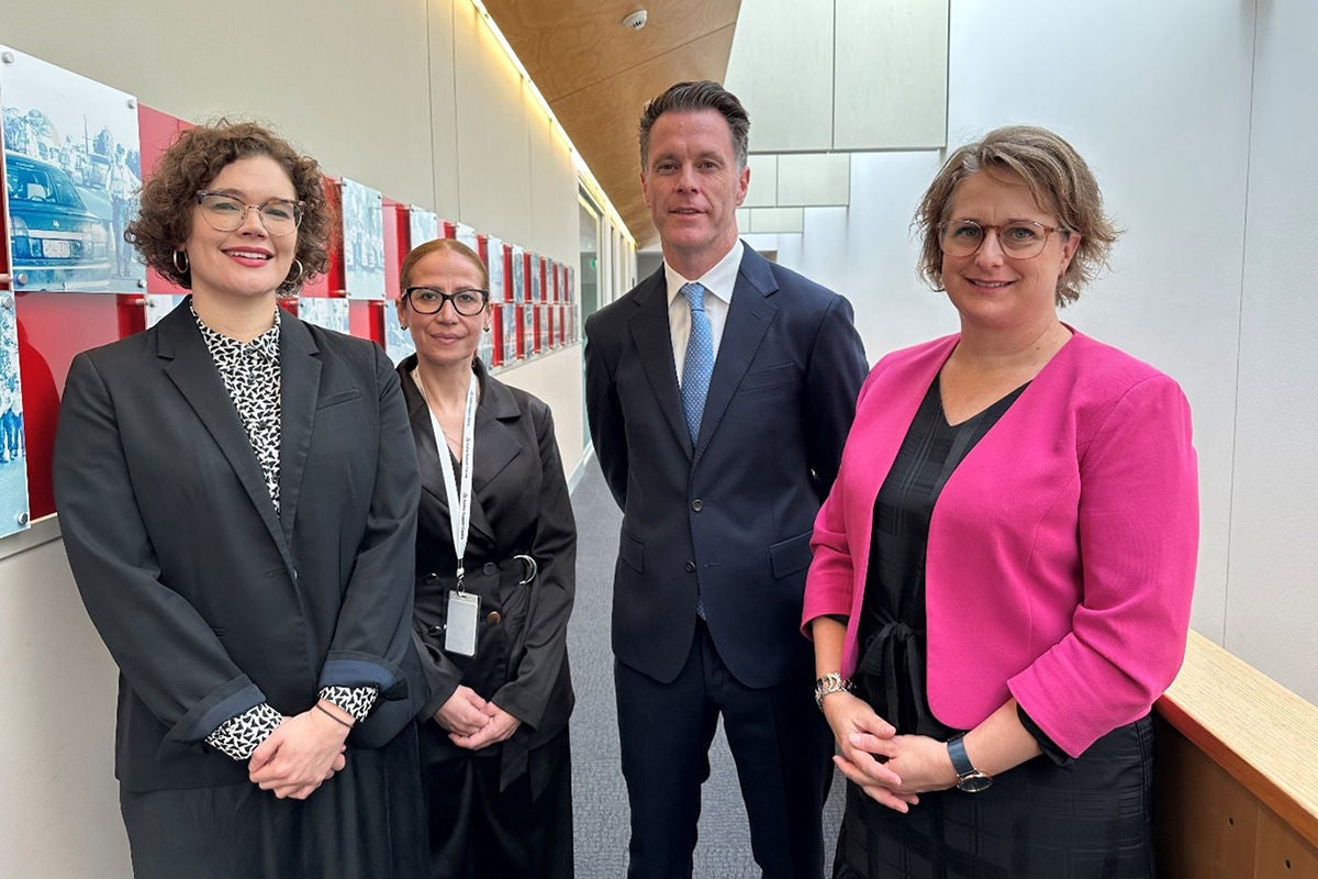 Four professional people standing in the hallway of an office smiling