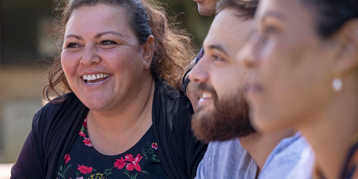 Close-up of aboriginal students and their tutor sitting outdoors in Australia.