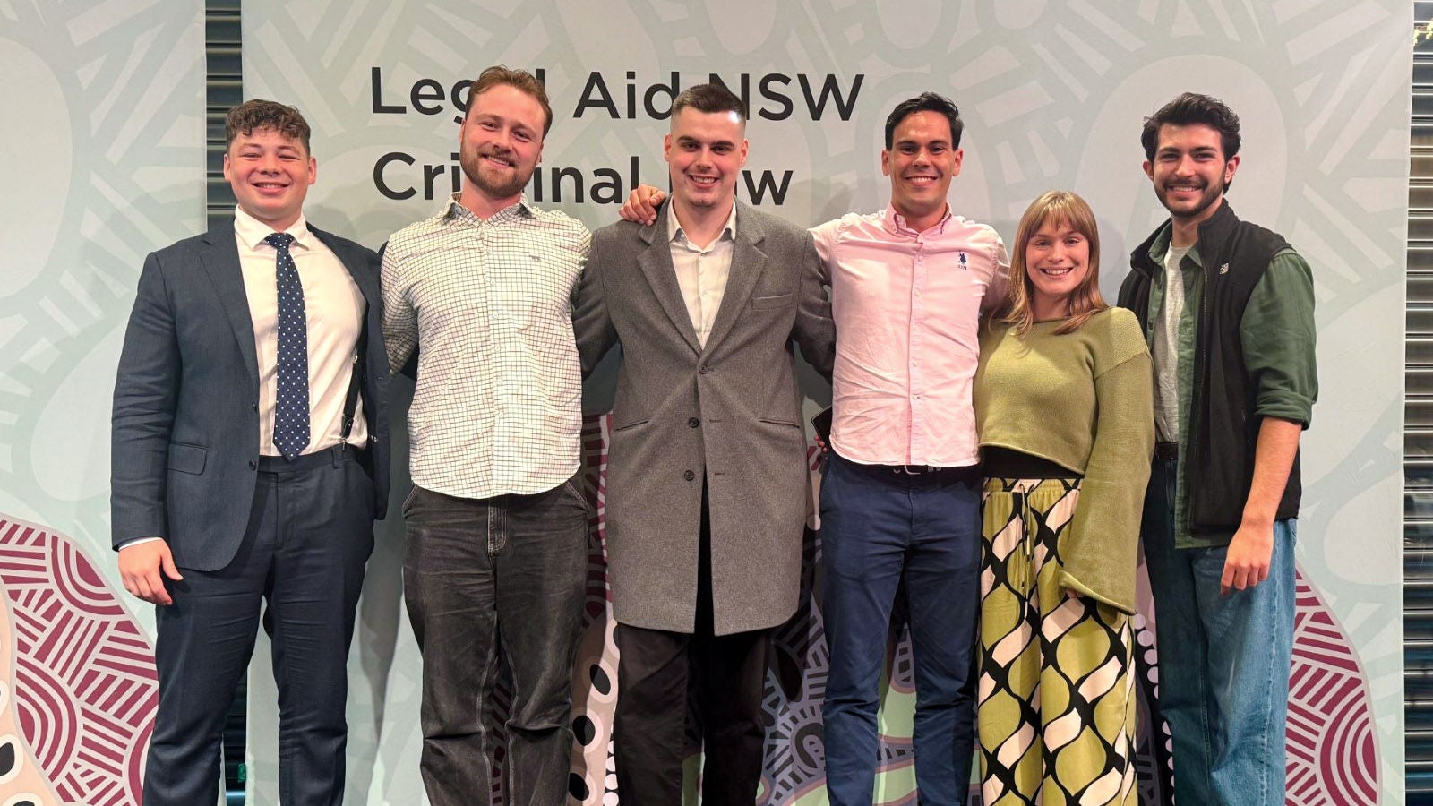 Six graduates from the Crime Regional Graduate Program standing together, smiling at the camera.