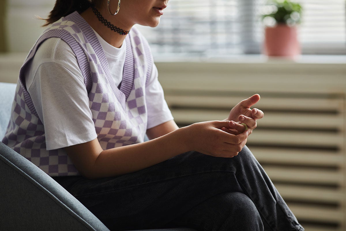 Woman sitting down with hands together feeling concerned 