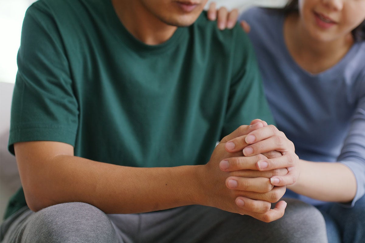 two people sitting together with their hands clasped together with only the bottom part of their faces showing